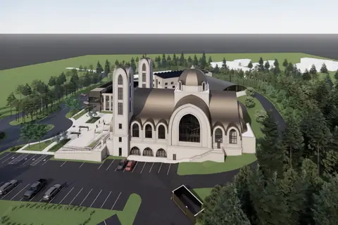 A low aerial rendering across the car park toward the three buildings, trees along the boundary.