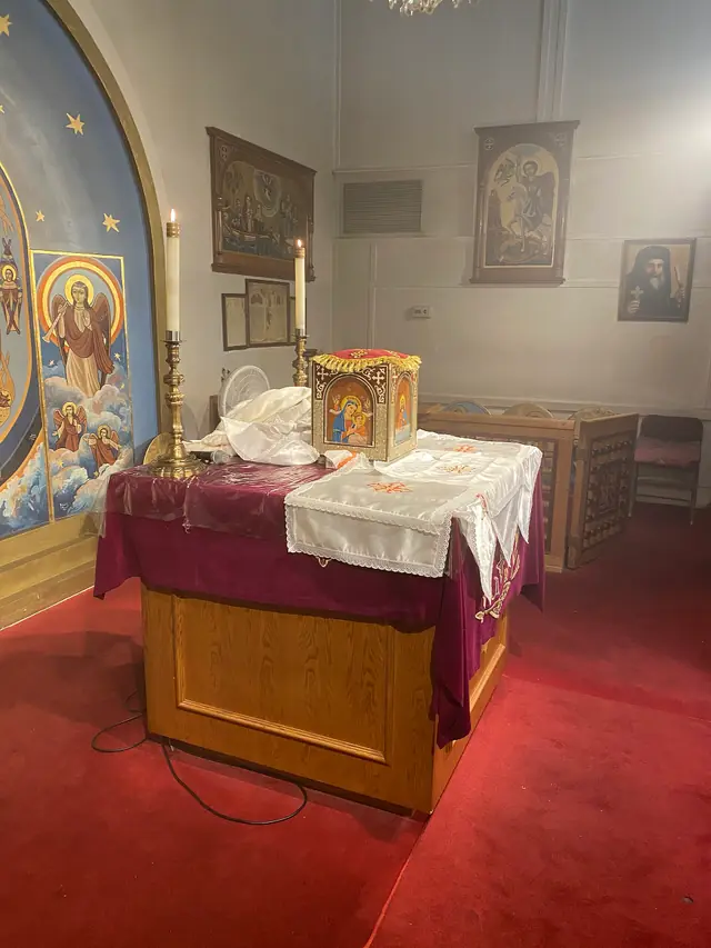 A Coptic altar under a painted apse, with a small decorated wooden box standing on it.