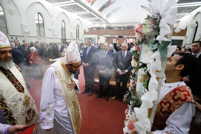 Two bishops in embroidered white copes and tall embroidered hats, incense smoke in the air.