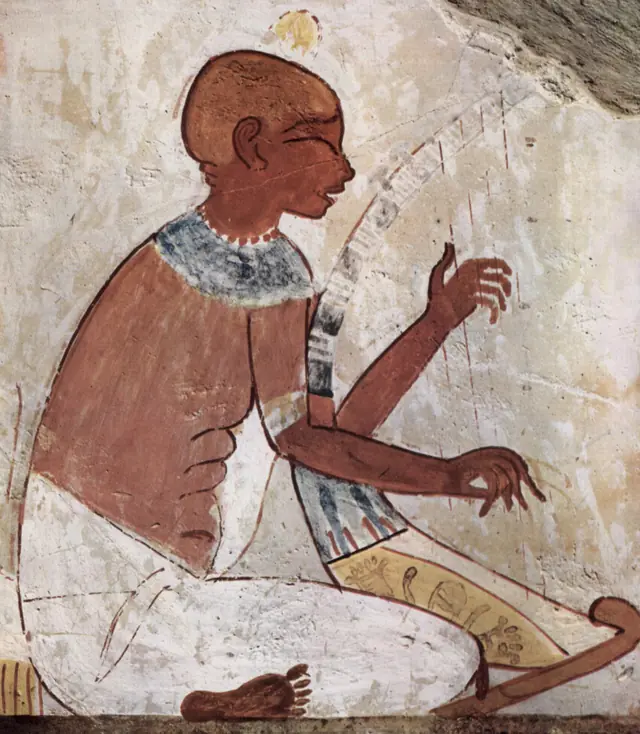 An ancient Egyptian tomb painting of seated women playing a double flute and other instruments.