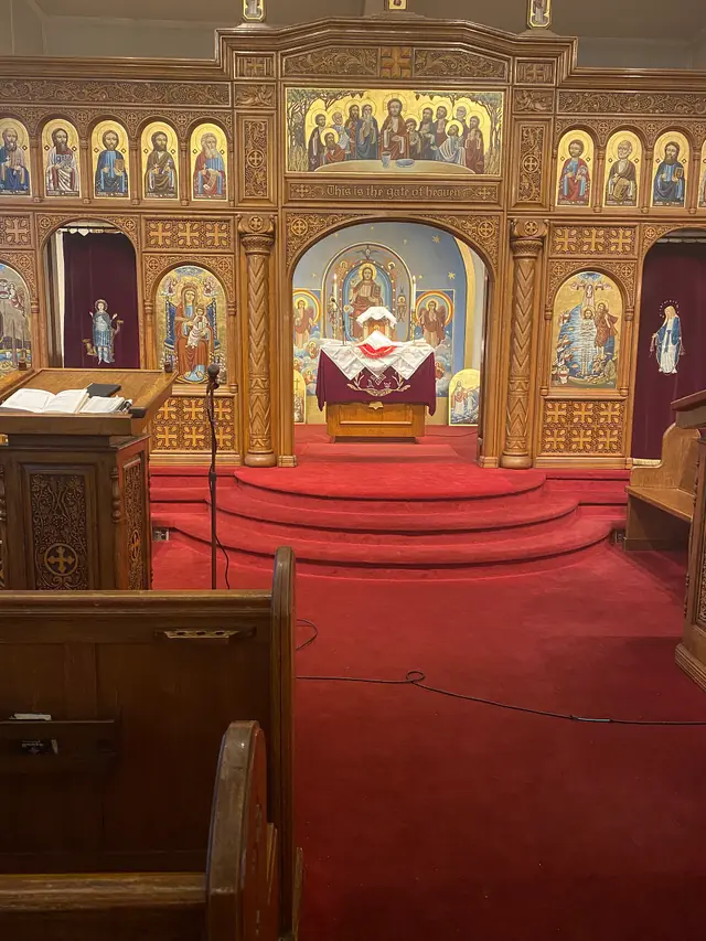 The carved wooden icon screen of a Coptic church, with the altar visible through its central arch.