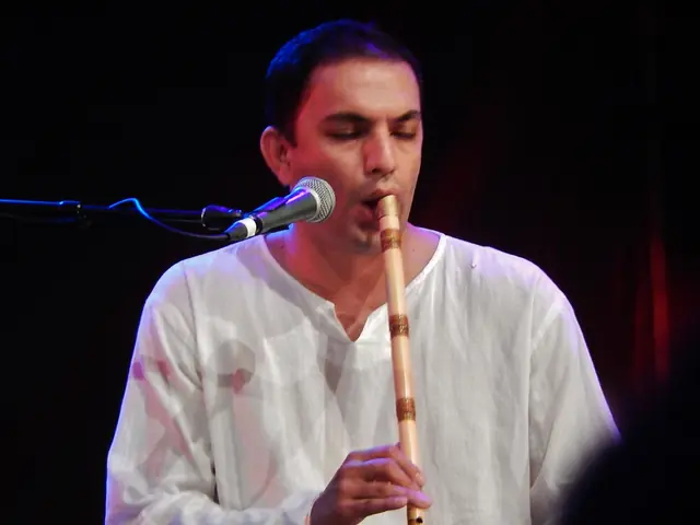 A musician holding a ney at an angle to the mouth, playing.